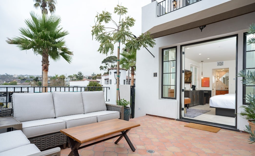 Outdoor patio with furniture showing a large bedroom through open French doors