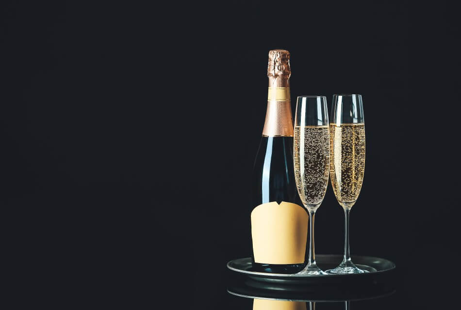 Bottle of champagne next to two flutes of champagne on a black round table