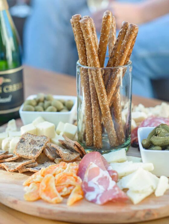 Charcuterie plate with dried meat, cheese, and crackers on a cheese board