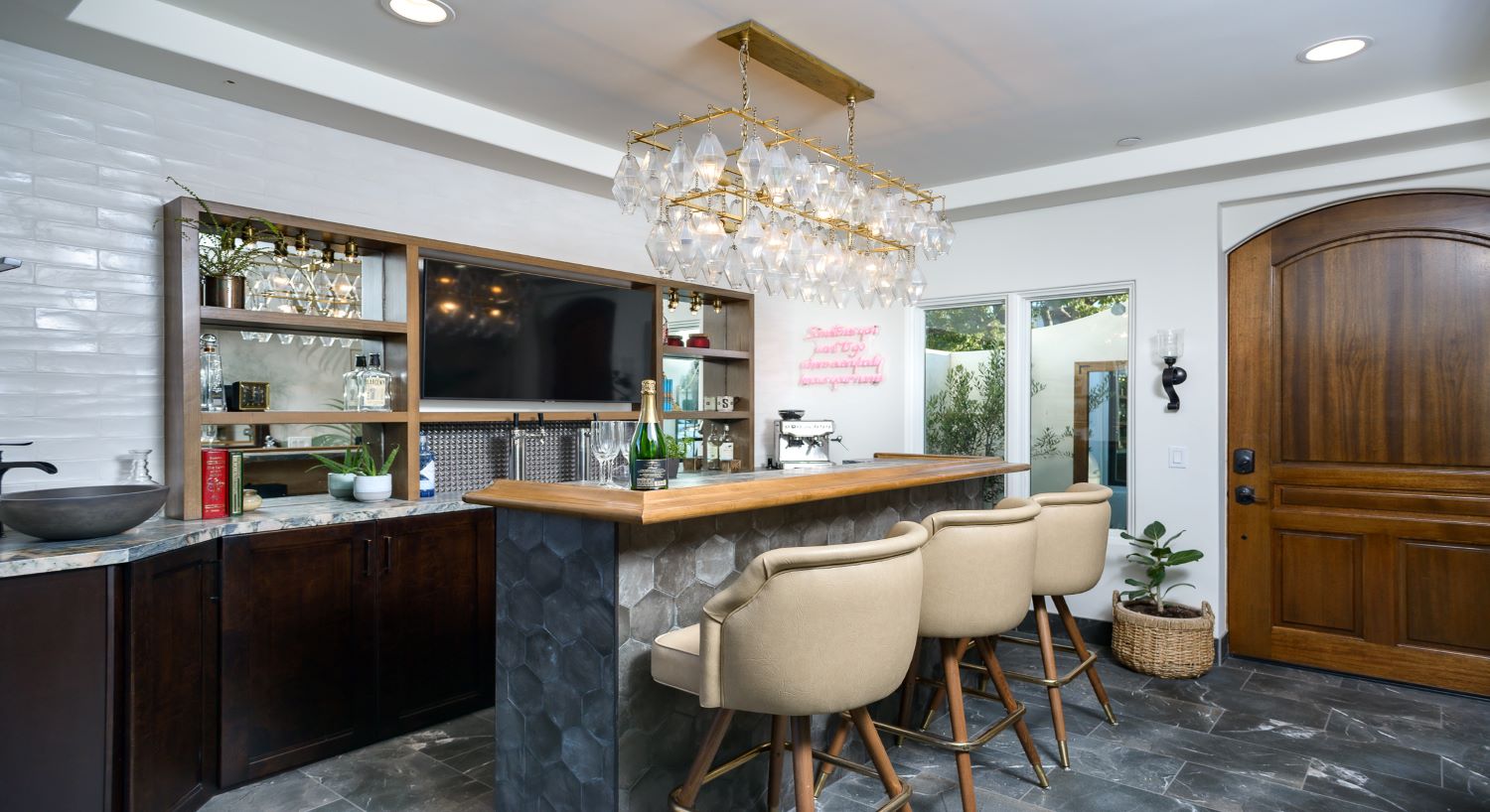 Bar area with glass chandelier, cream leather stools, and front entry door to outside